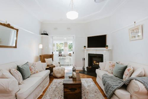 a living room with white furniture and a fireplace at The Cottage on Lawson - Heritage Elegance in Mudgee in Mudgee