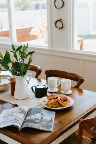 a table with a plate of pastries and a book at The Cottage on Lawson - Heritage Elegance in Mudgee in Mudgee