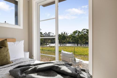 a bedroom with a bed and a window and a chair at Alkira Cottage in Ballandean
