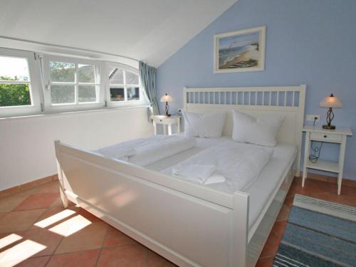 a white bed in a room with two windows at Störtebeker Comfortable holiday residence in Middelhagen
