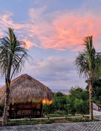 a hut with a palm tree and two palm trees at Samsara Penida in Batununggul
