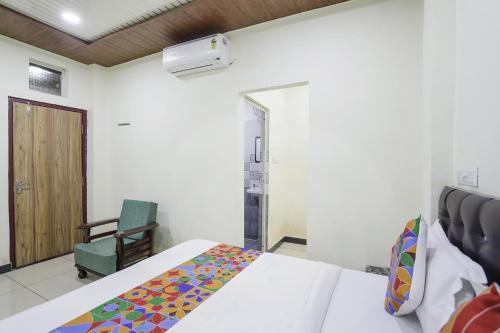 FabExpress Sai Palace في رايبور: غرفة نوم بسرير وكرسي أخضر