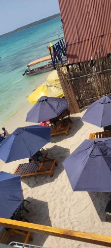 un groupe de chaises et de parasols sur une plage dans l'établissement Miramar Baru, à Barú