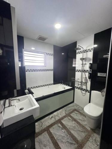 a bathroom with a tub and a sink and a toilet at H&H Homestay Premium House in Kepala Batas