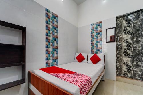 - une petite chambre avec un lit et des oreillers rouges dans l'établissement OYO Pothini Palace, à Palni