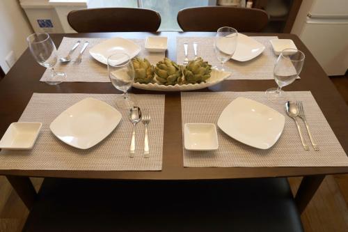 a table with white plates and silverware and a bowl of food at くつろぎのお宿 やわや toyama in Sakurabashidōri