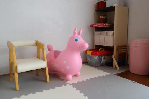 a toy pink pig next to a chair and a box at くつろぎのお宿 やわや toyama in Sakurabashidōri