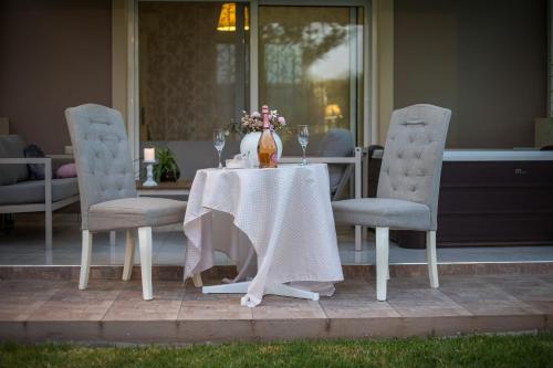 a table with two chairs and a vase on it at Sea Breeze & Nature villa ,near the sea, luxury jagguzi and spa private garden in Kremasti