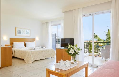 um quarto com uma cama, uma televisão e uma varanda em Renaissance Hanioti Resort em Chaniotis