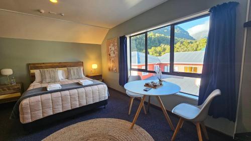 Franz Josef Montrose Lodge في فرانز جوزيف: غرفة نوم بسرير وطاولة ونافذة كبيرة