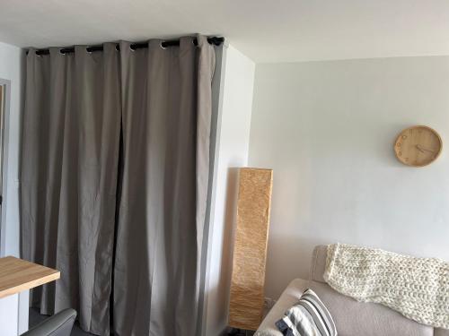 une chambre avec un rideau et une horloge sur le mur dans l'établissement Studio vue mer sur le port de Perros-Guirec, à Perros-Guirec