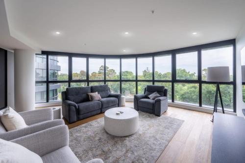 a living room with two couches and a table at Luxury Melbourne 4 Bed Apt - Pool and Parking in Melbourne