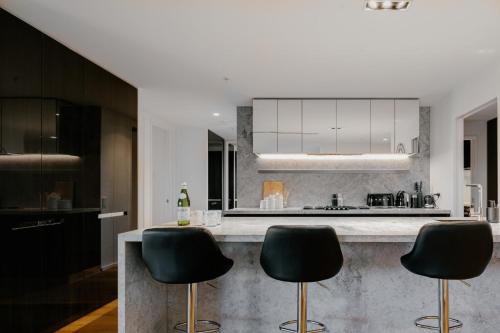 a kitchen with three black chairs at a counter at Luxury Melbourne 4 Bed Apt - Pool and Parking in Melbourne