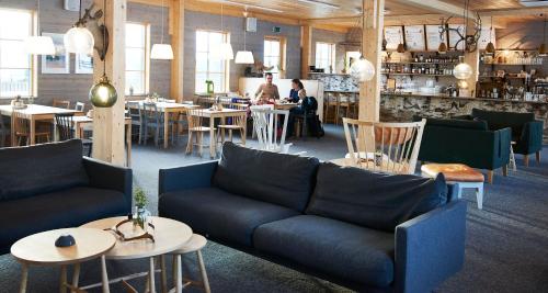 un restaurante con sofás y mesas y un bar en Tännäskröket, en Tännäs