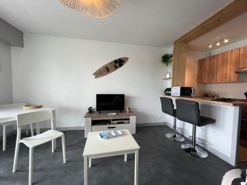 une cuisine avec des tables et des chaises blanches ainsi qu'un comptoir dans l'établissement Studio vue mer sur le port de Perros-Guirec, à Perros-Guirec