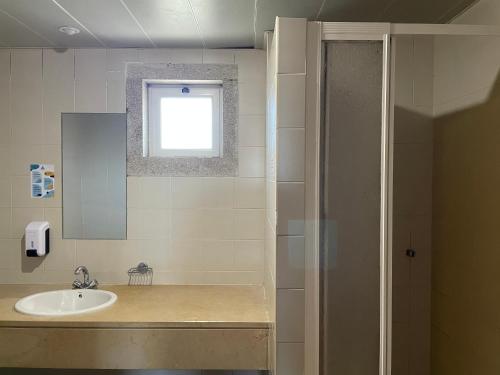 a bathroom with a sink and a shower with a window at HI Bragança – Pousada de Juventude in Bragança