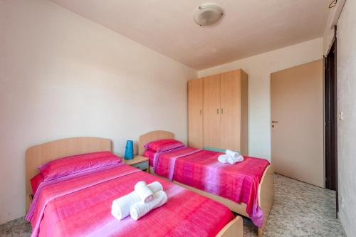 two beds in a room with red sheets and white towels at Zoilen in San Pietro in Bevagna