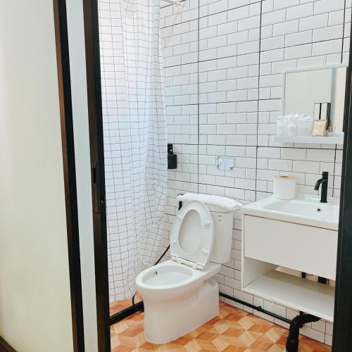 a white bathroom with a toilet and a sink at Penguin Villa Resort & Bistro in Ratchaburi