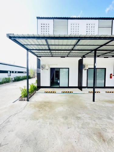 a large white building with a large metal roof at Penguin Villa Resort & Bistro in Ratchaburi