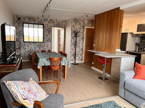 un salon avec une table et un canapé et une cuisine dans l'établissement Perle Marine - Lumineux Confortable 6p Bord de Mer, à Courseulles-sur-Mer