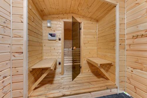 uma sauna de madeira com dois bancos e uma porta em Domki i pokoje Angelo z sauną i jacuzzi- Karwia em Karwia