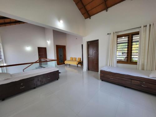 Habitación grande con 2 camas y sofá en Charvi Villa Stay - 3BH, Home Food, Campfire, en Chikmagalur