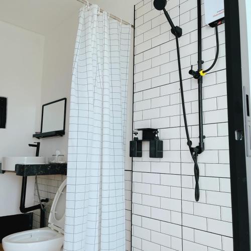 a bathroom with a shower with a white tiled wall at Penguin Villa Resort & Bistro in Ratchaburi