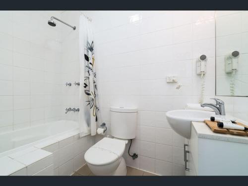 een witte badkamer met een toilet en een wastafel bij 29b Casa DeGregory, In the heart of Parap in Parap