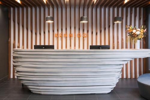 a lobby with a large white counter with chairs at Kennigo Hotel Brisbane, Independent Collection by EVT in Brisbane