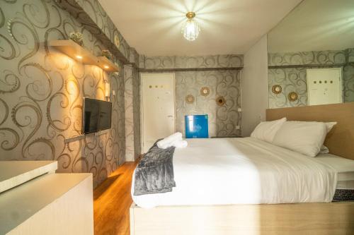 a bedroom with a white bed and a tv at Lovely Studio at Bassura City Netflix and chill in Jakarta