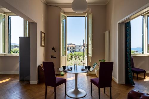 una sala da pranzo con tavolo, sedie e ampie finestre di Acquaviva Apartments a Livorno
