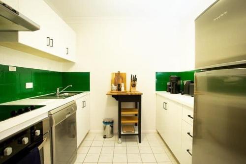 a kitchen with green walls and white counter tops at Fully Renovated 1Bdr Apt in Northbridge in Perth
