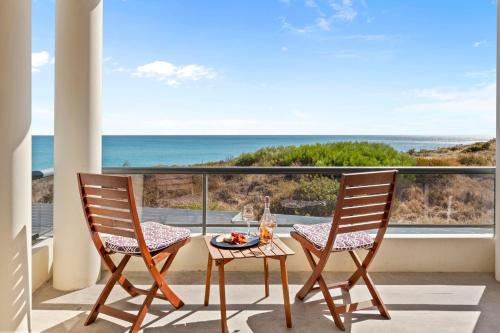 a table and two chairs on a balcony with the ocean at Beachfront Escape Private Pool and Beach Access in Mandurah