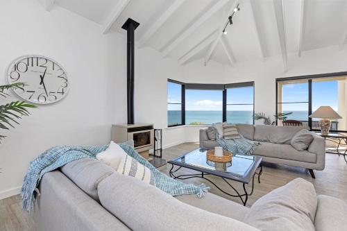 a living room with a couch and a clock on the wall at Beachfront Escape Private Pool and Beach Access in Mandurah