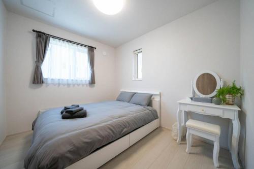 a bedroom with a bed and a table and a mirror at Lumiere Vista in Sapporo