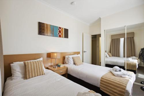 a hotel room with two beds and a mirror at Spacious Apt in Northbridge with Pool in Perth