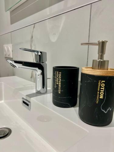 two black cups sitting on a bathroom sink at L'Opéra, T2 Cœur Ville in Anse
