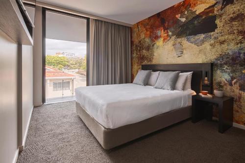 a bedroom with a large bed and a large window at Kennigo Hotel Brisbane, Independent Collection by EVT in Brisbane