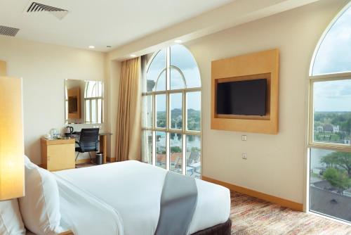 um quarto de hotel com uma cama e uma grande janela em The Waterfront Hotel Kuching em Kuching