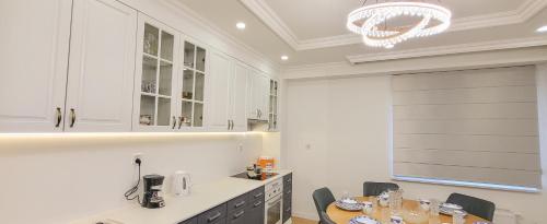 a kitchen with white cabinets and a table and chairs at Mogul Tower Apartment, UB center in Ulaanbaatar
