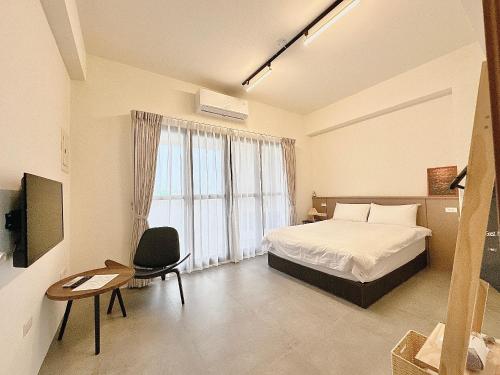ein Schlafzimmer mit einem Bett, einem Stuhl und einem Fenster in der Unterkunft 一玖玖一民宿 1991 in Magong