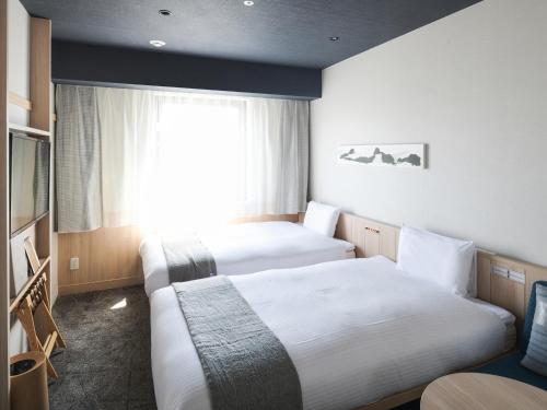 a hotel room with two beds and a window at Vessel Hotel Campana Susukino in Sapporo
