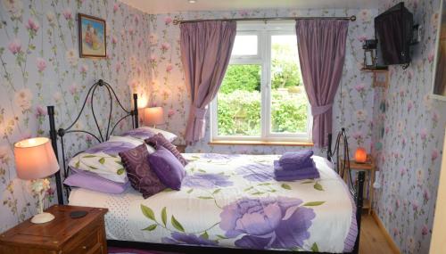 a bedroom with a bed with purple pillows and a window at Dawn in Hemsby