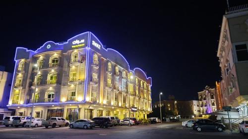 un edificio iluminado con coches estacionados en un estacionamiento en Swat Hotel Apartments 2, en Al Khobar