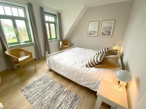 Schlafzimmer mit einem weißen Bett, einem Tisch und Fenstern in der Unterkunft Ferienhaussiedlung Strandperlen Weidenhof 3b (Typ VI) in Wustrow