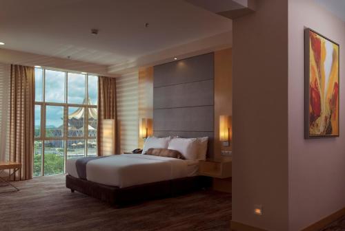 クチンにあるThe Waterfront Hotel Kuchingのベッドと大きな窓があるホテルの部屋