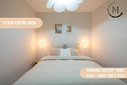 a white bedroom with a bed and a chandelier at La Madeleine, T2 Cœur Ville in Anse