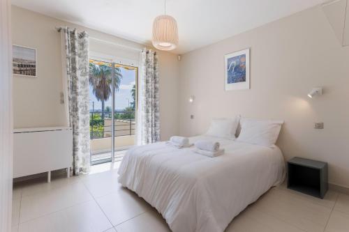 une chambre blanche avec un grand lit et une fenêtre dans l'établissement Villa Cynthia - Piscine - Plage (à 50m) - Palais Congrès - Calme absolu, à Cannes