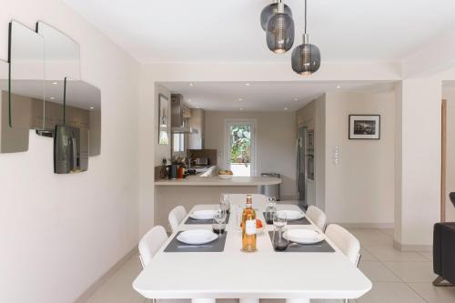 une cuisine et une salle à manger avec une table et des chaises blanches dans l'établissement Villa Cynthia - Piscine - Plage (à 50m) - Palais Congrès - Calme absolu, à Cannes