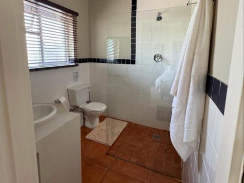a white bathroom with a toilet and a sink at Moments B&B Guesthouse, Kleinmond in Kleinmond